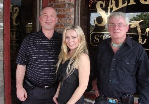 Two men and a woman are posing for a picture in front of a sign that says salvation