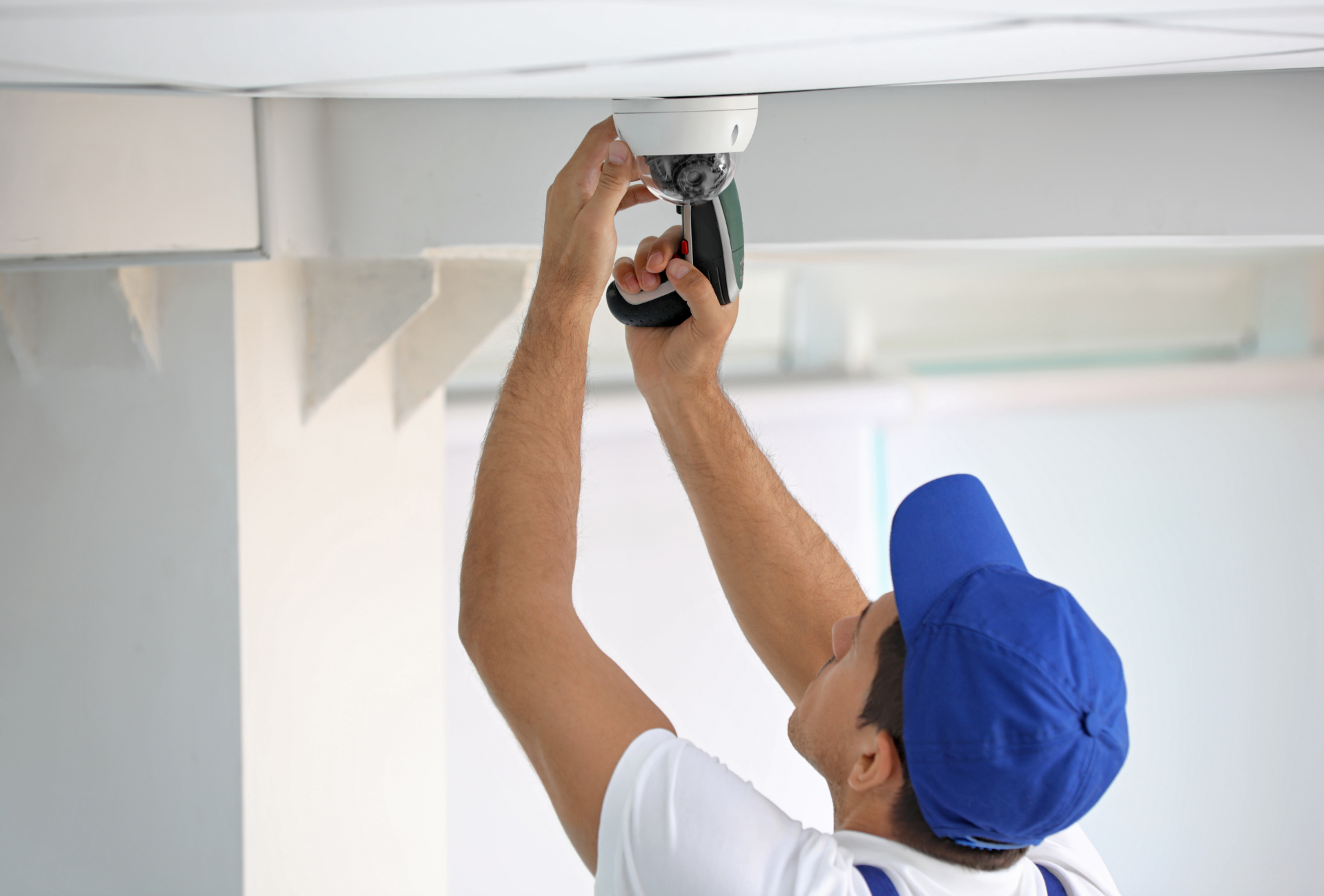 A man is installing a fire alarm on the ceiling.